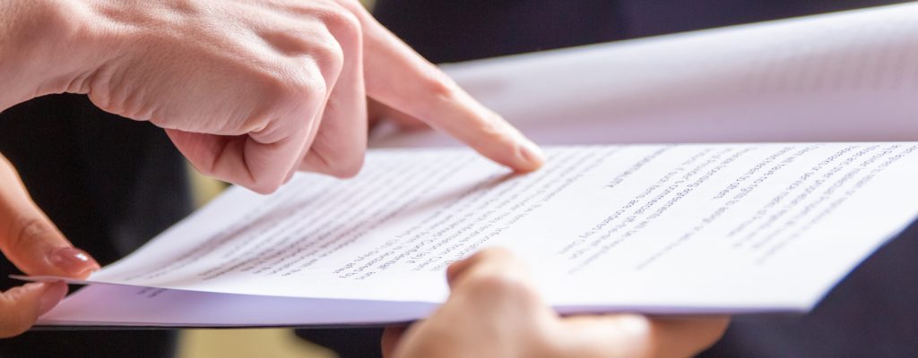 Cropped view of businesswomen reading document. Closeup shot of female finger pointing at page. Business concept